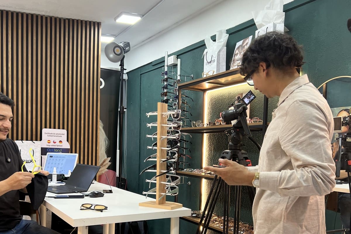 Equipo Vortice en Ópticas Distavid — Eithan revisando cámara en tienda con vitrinas de monturas iluminadas, La Serena