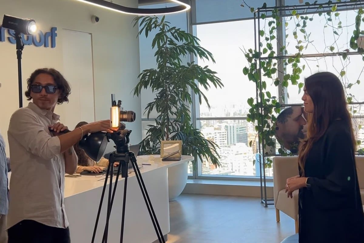 Producción corporativa Vortice — Eithan con luz y sujeto frente a ventanales con skyline, oficina Weindorf, Santiago